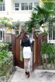 A woman standing in front of a wooden gate.