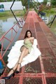 A woman in a green dress is sitting on a white rug.