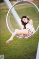 A woman sitting in a hanging chair in a park.