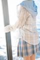 A woman standing by a window looking out at the ocean.