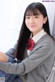 A young woman in a school uniform sitting on a chair.