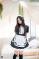 A woman in a black and white maid outfit posing on a bed.