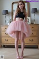 a woman in a black top and pink skirt posing for a picture