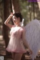 A woman in a pink dress with white angel wings.