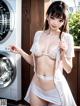 A woman in a white lingerie standing next to a washing machine.