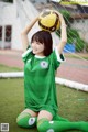 A woman in a green soccer uniform holding a soccer ball.