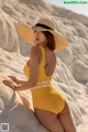 A woman in a yellow bathing suit and a straw hat.