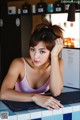 A woman in a pink tank top leaning on a counter.